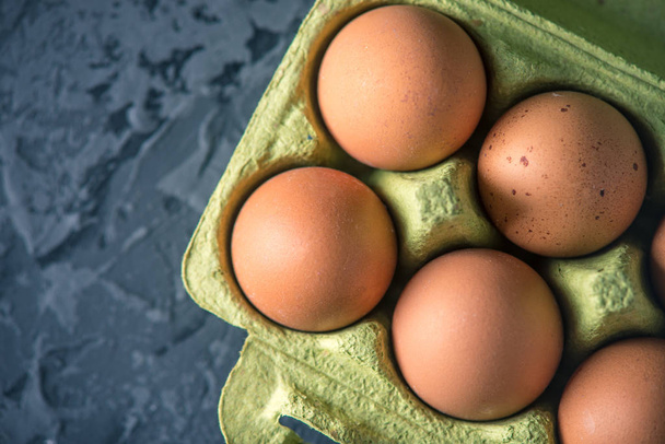 Fresh farm eggs in green tray, on beautiful dark background. Home eco-friendly products - Fotoğraf, Görsel