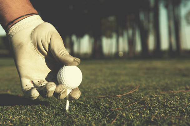 close up of golf players hand placing ball on tee - Foto, imagen