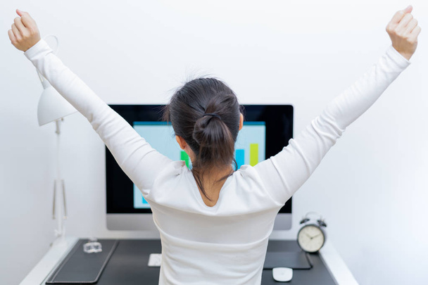 Young Asian beautiful woman sitting in front of computer and stretch oneself after long working. stress-free and relax - Photo, Image