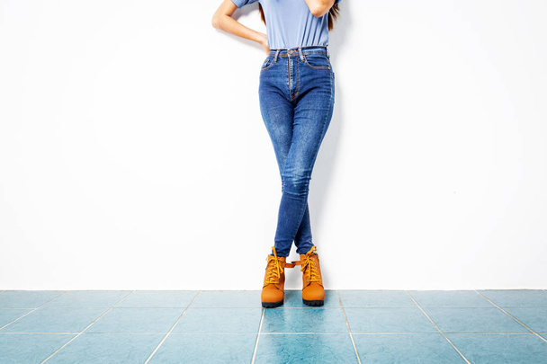 Young girl blue jeans brown shoes wall white. - Photo, image