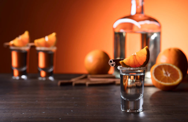 Vasos de tequila con palitos de naranja y canela en una t de madera
 - Foto, imagen