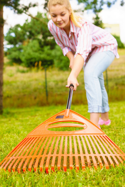 Woman using rake to clean up garden - Fotó, kép