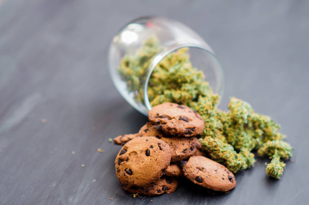 Cookies with cannabis and buds of marijuana on the table. Copy Space Concept of cooking with cannabis herb. Treatment of medical marijuana for use in food, On a black background - Photo, Image
