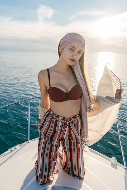 luxurious stylish girl stands on a white yacht, sails to the Caribbean islands and poses, vacation - Fotó, kép