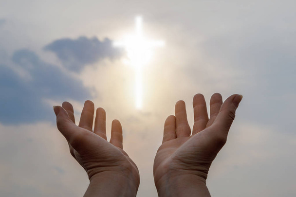 Las manos alcanzan el cielo a la luz en forma de cruz
. - Foto, imagen