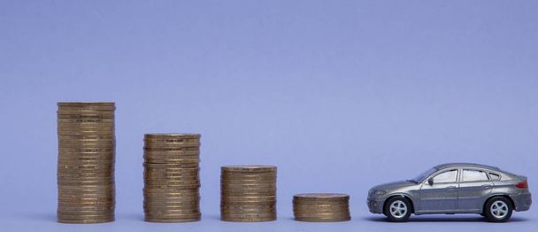Szary model samochodu z monet w postaci histogramu na fioletowym tle. Koncepcji pożyczek, oszczędności, ubezpieczenia - Zdjęcie, obraz