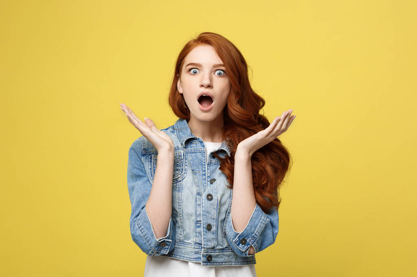 Lifestyle Concept: Surprised young woman with hand on side over golden yellow background. Looking at camera. - Φωτογραφία, εικόνα