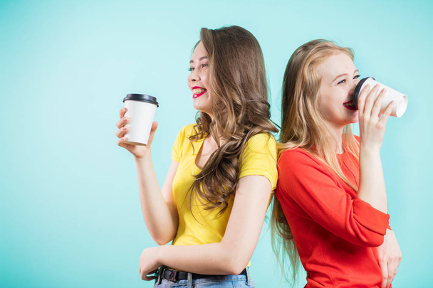 Two smiling students having a cup of coffee. happy young women laugh, back to back - Foto, imagen