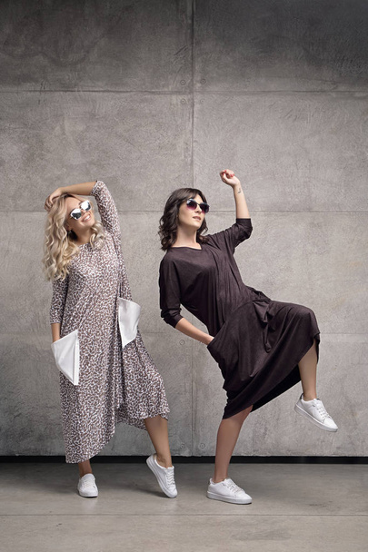 Two cheerful trendy young women wearing sunglasses - Foto, imagen