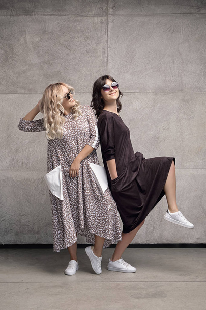 Twee vrolijke trendy jonge vrouwen dragen van een zonnebril - Foto, afbeelding