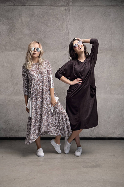 Duas jovens mulheres alegres e na moda usando óculos de sol
 - Foto, Imagem