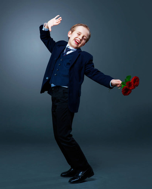 hansome boy wearing a black suit with roses in his hands  - Photo, Image