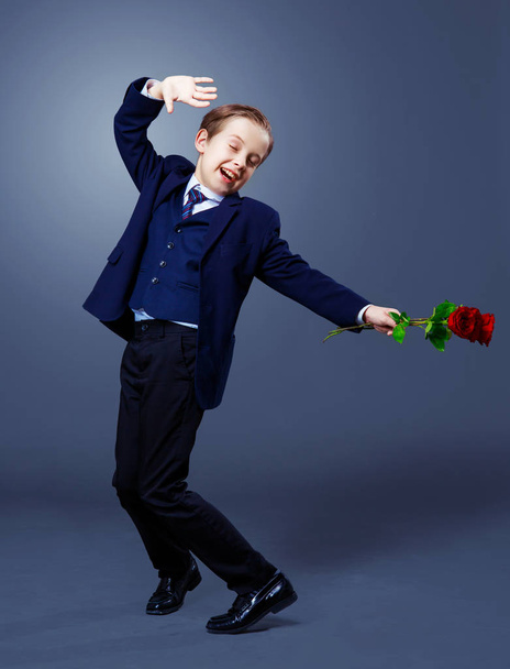 hansome boy wearing a black suit with roses in his hands  - 写真・画像
