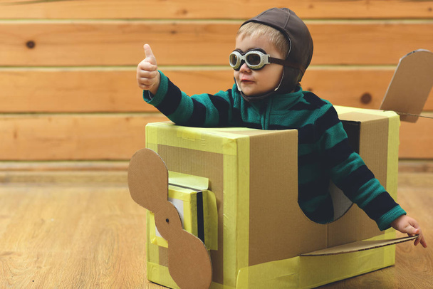 Little boy child play in cardboard plane, childhood. Pilot travel, airdrome, imagination. Kid, pilot school, innovation. Air mail delivery, aircraft construction. Dream, career, adventure, education. - Foto, Imagen