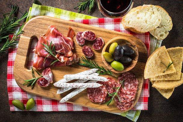 Antipasto viipaloitu liha, kinkku, salami, oliivit tummalla kivipöydällä
 - Valokuva, kuva