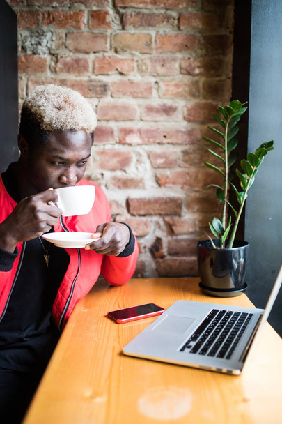 Muotokuva onnellisesta afroamerikkalaisesta miehestä juomassa aamukahvia kahvilassa.
 - Valokuva, kuva