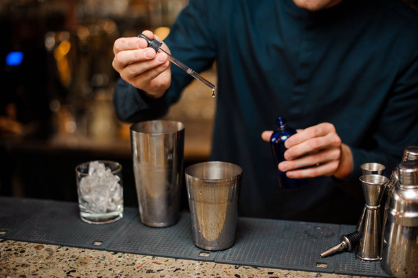 Barman adding blue dye into a shaker making summer cocktail - Foto, afbeelding