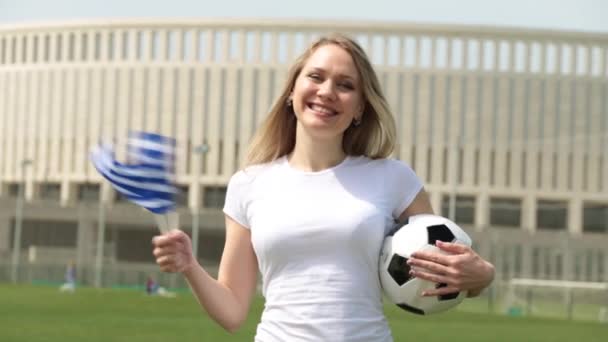 Tifoso di calcio con la bandiera della Grecia. Donna con bandiera greca e pallone da calcio
. - Filmati, video