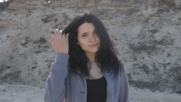 genç bir esmer kadın kum bir arka plan üzerine açık portresi - Video, Çekim