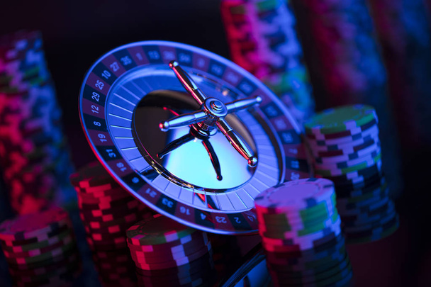 Tema del gioco d'azzardo. Roulette e poker chips su sfondo colorato bokeh
. - Foto, immagini