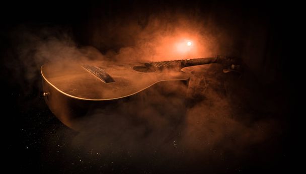 Концепция музыки. Акустическая гитара на тёмном фоне под лучом света с дымом. Гитара со струнными, закрывай. Выборочный фокус. Пожарные. Сюрреалистичная гитара
 - Фото, изображение