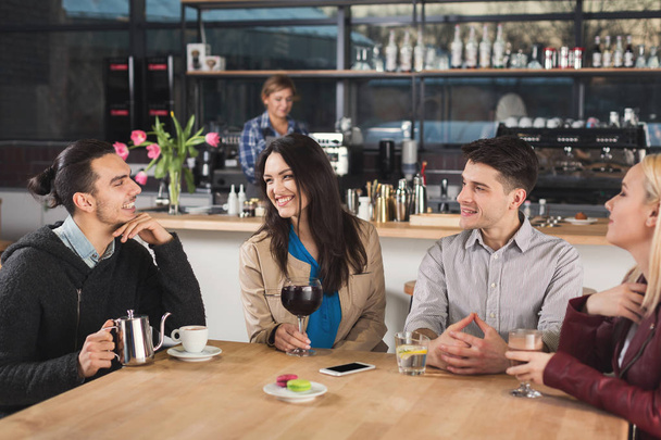 Счастливые молодые друзья пьют кофе в кафе
 - Фото, изображение