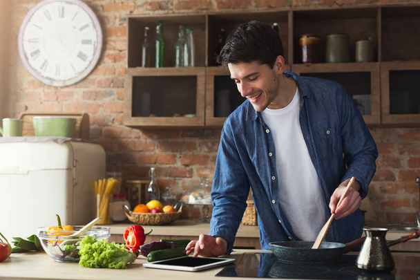 Hombre feliz preparando comida saludable en la cocina casera
 - Foto, imagen