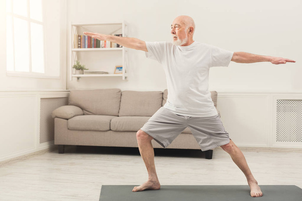 Vanhempi mies harjoittelee joogaa sisätiloissa
 - Valokuva, kuva