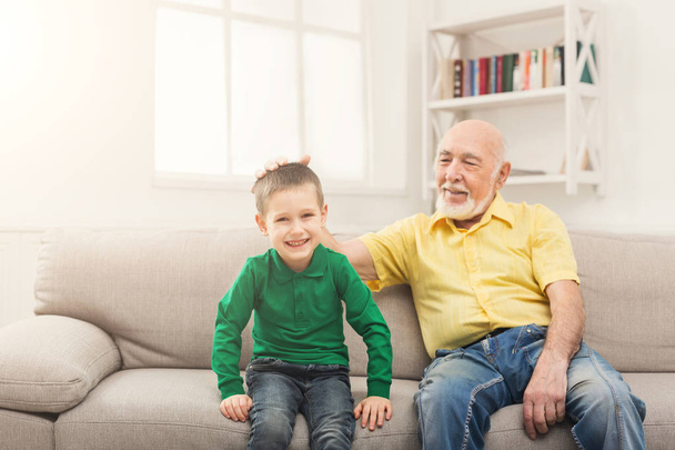Pieni poika istuu sohvalla isoisänsä kanssa
 - Valokuva, kuva