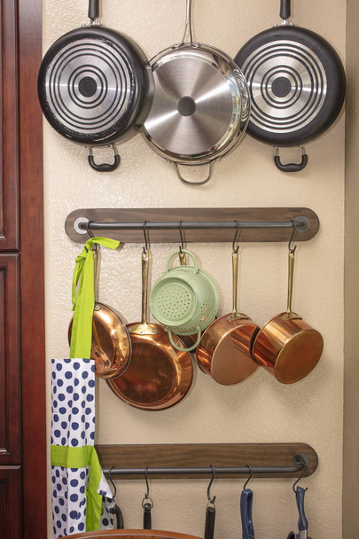 Горщики і сковороди, що звисають на стіні кухні, щоб заощадити місце
 - Фото, зображення