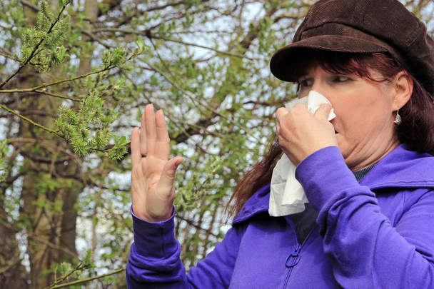 An older woman has hay fever. Hay fever begins in spring. A woman has a cold and is blowing into a handkerchief - Photo, Image