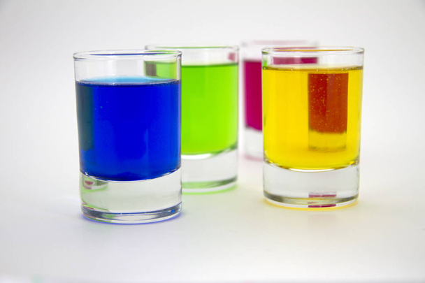 Multicolored glasses of different drinks. Party and holiday celebration concept. Four glasses with a blue, green, yellow and red drink. Isolated on white background. - Φωτογραφία, εικόνα