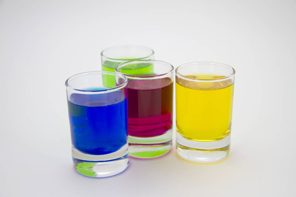 Multicolored glasses of different drinks. Party and holiday celebration concept. Four glasses with a blue, green, yellow and red drink. Isolated on white background. - Φωτογραφία, εικόνα