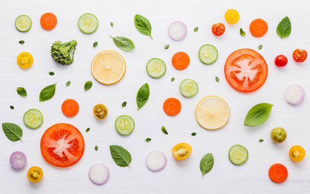 Τρόφιμα μοτίβο με πρώτες ύλες της σαλάτας, φύλλα μαρουλιού, αγγούρια, ντομάτες, καρότα, μπρόκολο, βασιλικό, κρεμμύδι και λεμόνι επίπεδη θέσει σε λευκό ξύλινο φόντο. - Φωτογραφία, εικόνα