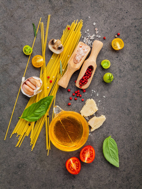 Έννοια ιταλικό φαγητό. Σπαγγέτι με συστατικά γλυκό βασιλικό, ντομάτα, σκόρδο πιπέρι, champignon, κολοκύθι και παρμεζάνα τυρί σε σκούρο φόντο επίπεδη lay και αντίγραφο χώρου. - Φωτογραφία, εικόνα