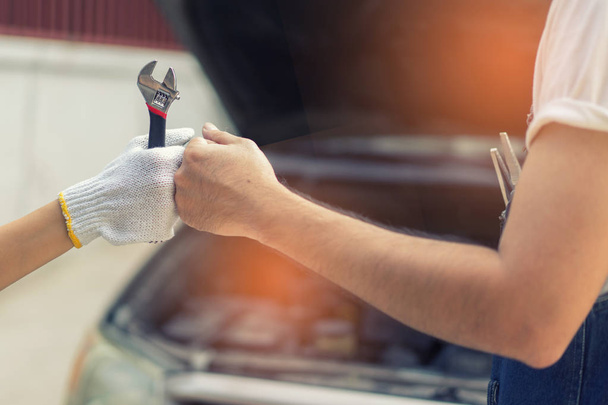 Mechanic hand checking and fixing a broken car in  garage.hand o - Zdjęcie, obraz