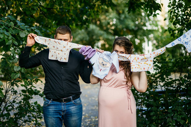 pregnancy, married young couple with baby clothes - Fotoğraf, Görsel