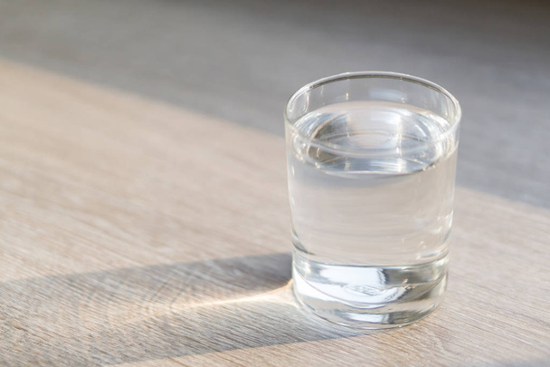 Egy pohár víz a fa asztalra világítással reggel, egészséges ellátás koncepció, szelektív fókusz - Fotó, kép