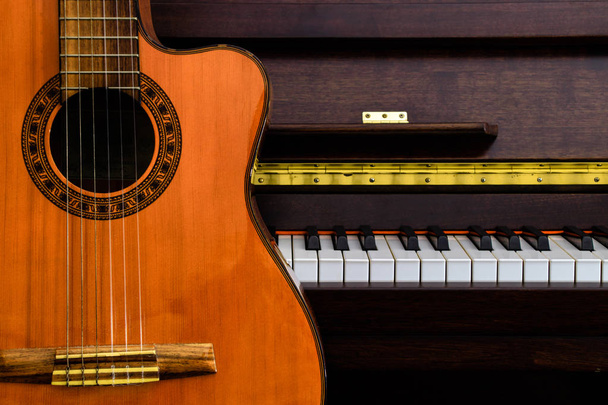 primo piano della chitarra classica sopra i tasti del pianoforte a coda per lo sfondo musicale con spazio di copia
 - Foto, immagini