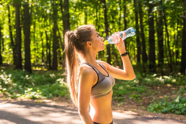 junge Frau trinkt Wasser nach dem Laufen im Freien - Foto, Bild