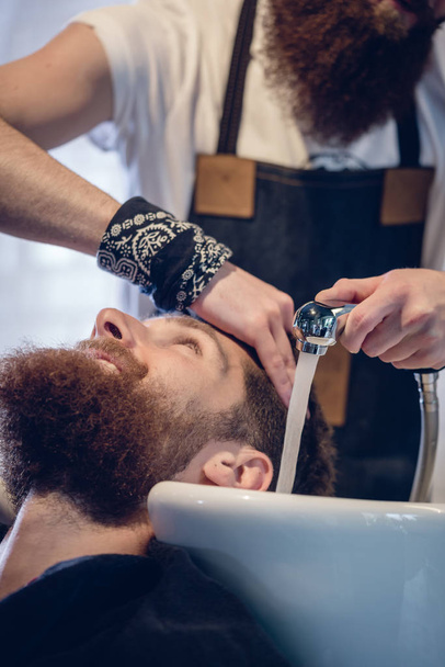 Primer plano de las manos de un peluquero experto que da un lavado de pelo al cliente
 - Foto, Imagen