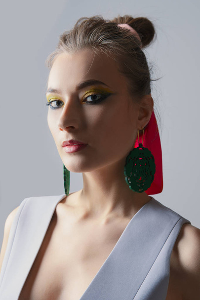 Portrait of beautiful fashion model in sleeveless jacket. Bright makeup and big earrings - Photo, Image