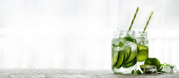 Homemade lime lemonade with cucumber, rosemary and ice, white background. Cold beverage for hot summer day. Copyspace. Banner - Valokuva, kuva