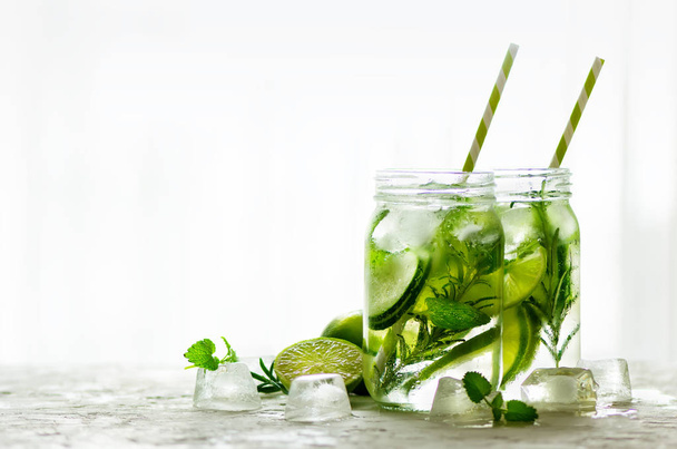 Cold and refreshing detox water with lime, cucumber, rosemary and ice in glass jar. Copyspace. - Foto, immagini
