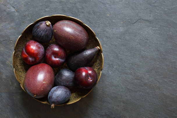 Dark Exotic Fruits on slate background including passion fruit, plums, figs, with copy space right - Фото, зображення