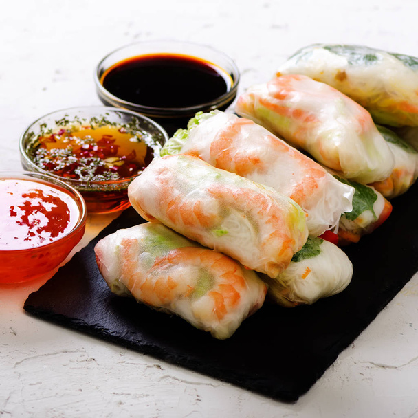 Vietnamese spring rolls - rice paper, lettuce, salad, vermicelli, noodles, shrimps, fish sauce, sweet chili, soy, lemon, veletables. Copy space. Asian and thai food. Traditional national cuisine. - Photo, Image