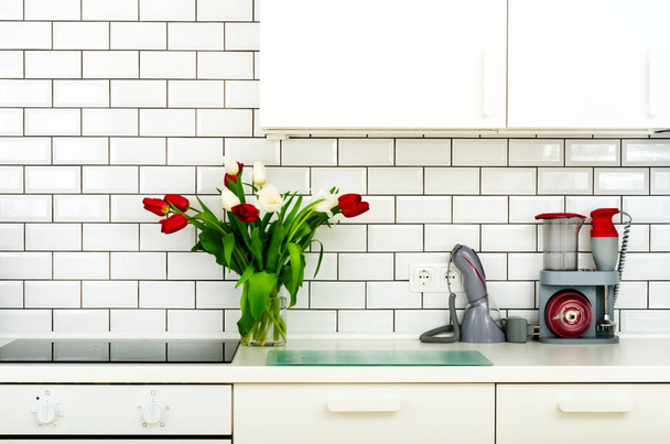 Fresh bouquet of red and white tulips on kitchen table. Detail of home interior, design. Minimalistic concept. Flowers for mother, girl, wife, woman. Copy space. - Photo, image