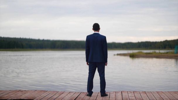 Liikemies katselee järveä. Klipsi. Takana näkymä liikemies tarkastellaan viehättävä luonto maisema. Liikemies seistä laiturissa
 - Valokuva, kuva