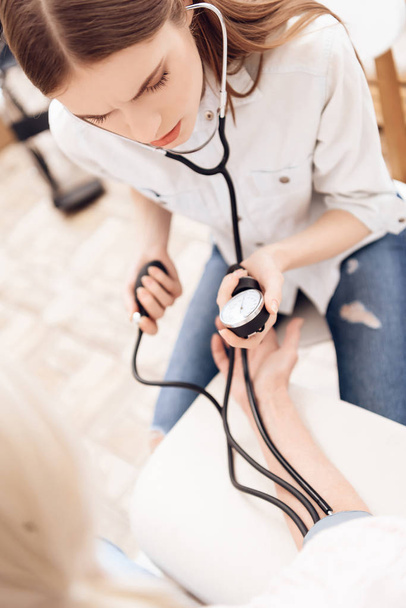 Dívka ošetřovatelství postarší žena a pomocí tonometr pro měření krevního tlaku - Fotografie, Obrázek