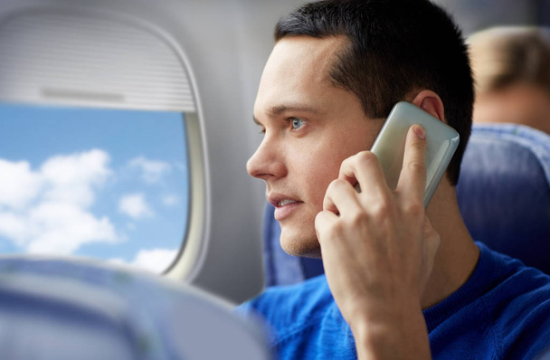 young man calling on smartphone in plane - Fotó, kép